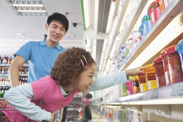 Klein meisje bereiken voor levensmiddelen in de supermarkt — Stockfoto