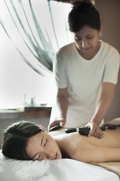 Jovem mulher recebendo massagem de pedra quente — Fotografia de Stock