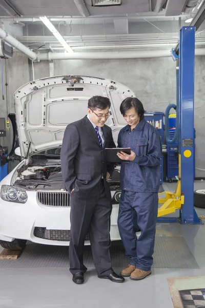 Empresario con mecánico en taller de reparación de automóviles — Foto de Stock