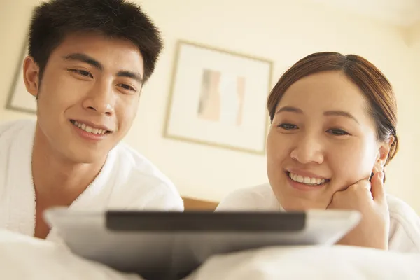 Pareja joven usando tableta en la cama — Foto de Stock