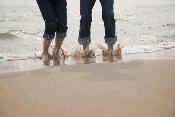 Jeune couple éclaboussures dans les vagues — Photo