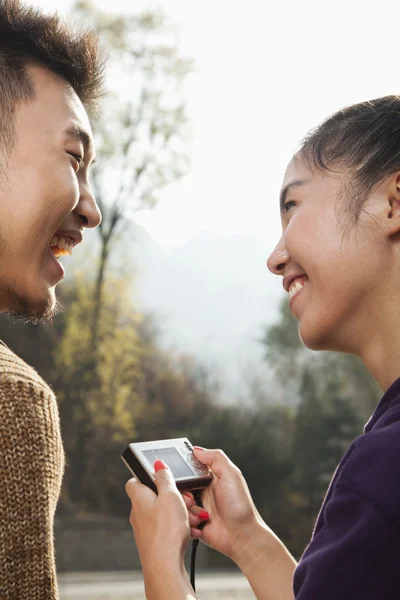 Young couple smiling, woman holding digital camera — Stock Photo, Image