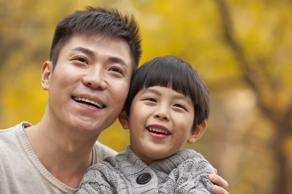 Vader en zoon glimlachend in het park in het najaar van — Stockfoto