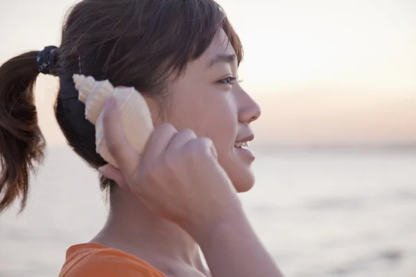 Genç kız Seashell için dinleme — Stok fotoğraf