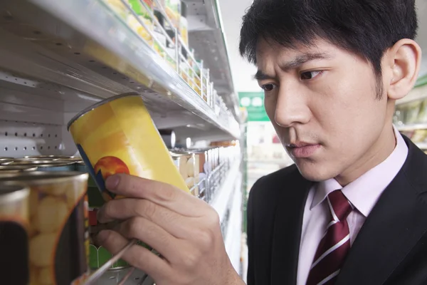 Geschäftsmann schaut sich Dose im Supermarkt an — Stockfoto