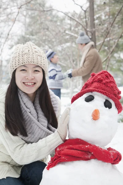 Matka dělat sněhuláka v zimě — Stockfoto
