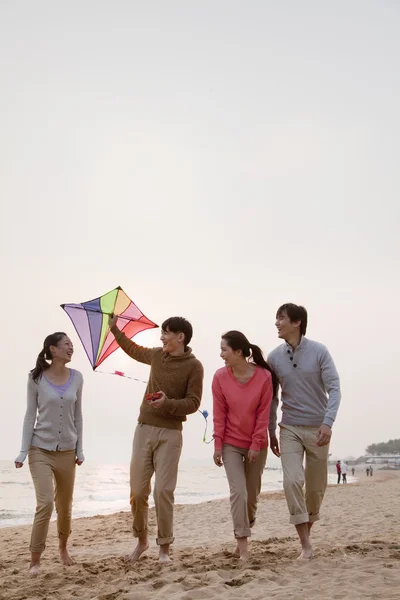 Jonge vrienden vliegen een vlieger op het strand — Stockfoto