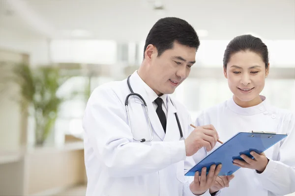 Arzt und Krankenschwester schauen sich Krankenakte an — Stockfoto