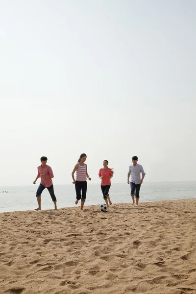 Unga vänner spela fotboll på stranden — Stockfoto