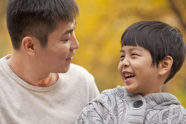 Vader en zoon glimlachend in het park in het najaar van — Stockfoto