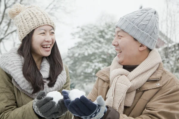 Paar houden sneeuw ballen in park — Stockfoto