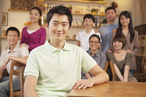 Portret van een jonge man met een groep vrienden op een koffieshop — Stockfoto