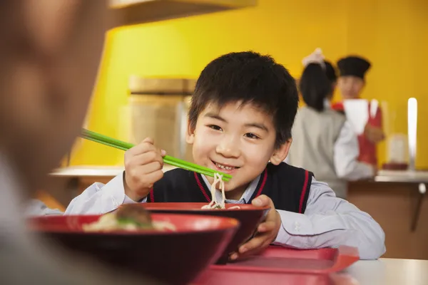 School boy eats noodles in school cafeteria — Stock Photo, Image