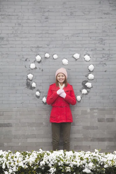Vrouw op muur met hartvormige sneeuw ballen — Stockfoto