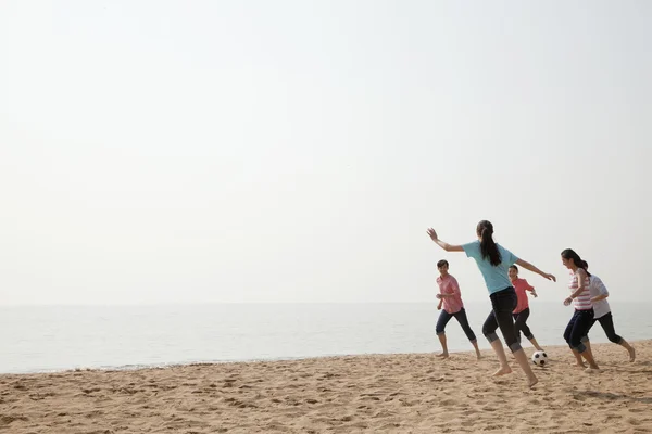 Молодые друзья играют в пляжный футбол — стоковое фото