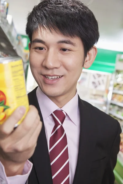 Businessman looking at can in the Supermarket — Stock Photo, Image