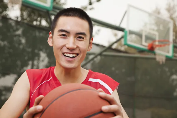 Jeune homme avec un ballon sur le terrain de basket — Photo