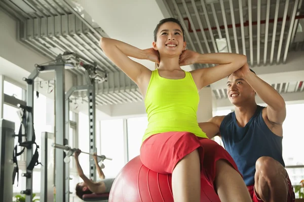 Unga kvinnor som tränar med hennes personliga tränare på gymmet — Stockfoto