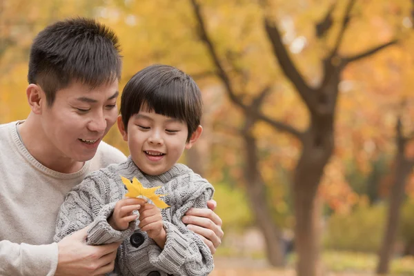 Father and son smiling in the park in autumn — Stock Photo, Image