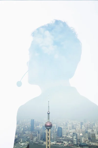 Double exposure of young businessman with headset and the skyline of Shanghai — Stock Photo, Image