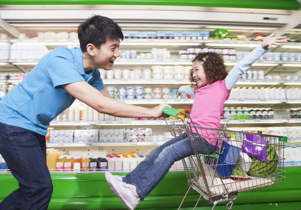 Vader duwen dochter in winkelwagen — Stockfoto