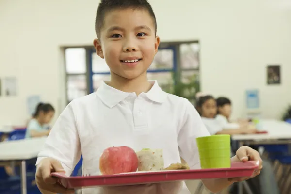 Escola menino segurando bandeja de comida — Fotografia de Stock