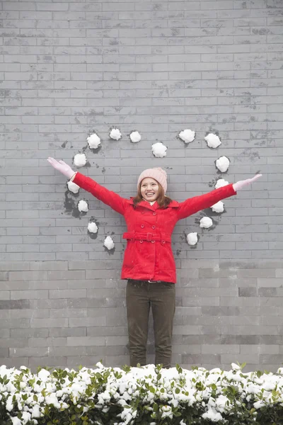 Vrouw op muur met hartvormige sneeuw ballen — Stockfoto