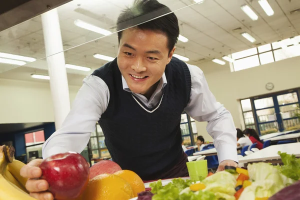 学校の食堂で健康に良い食べ物のために達する先生 — ストック写真