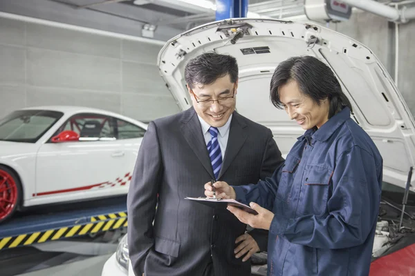 Empresario con mecánico en taller de reparación de automóviles — Foto de Stock