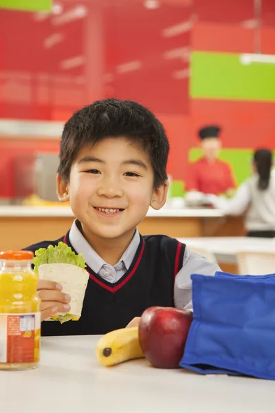 School boy eating lunch in school cafeteria — Stock Photo, Image