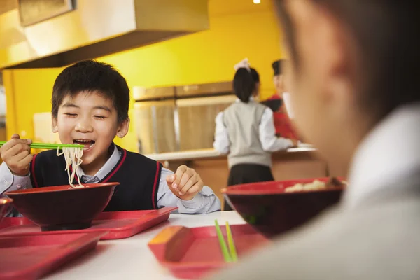 School boy eating noodles in school cafeteria — Stock Photo, Image