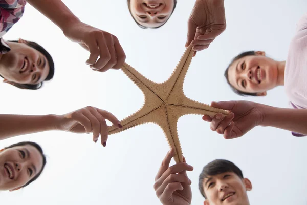 Grupo de amigos sosteniendo una estrella de mar — Foto de Stock