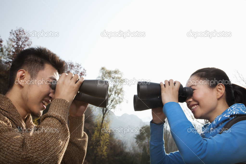 Couple looking at each other through binoculars