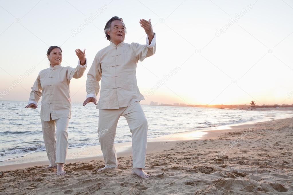 People practicing Taijiquan on the beach at sunset