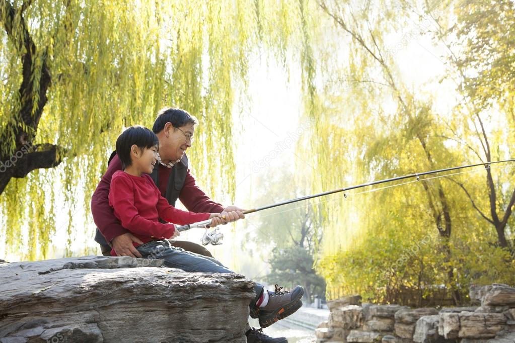 Grandfather and grandson fishing portrait at lake