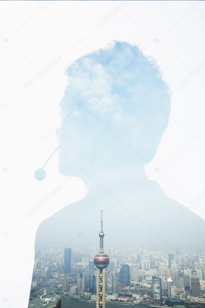 Double exposure of young businessman with headset and the skyline of Shanghai