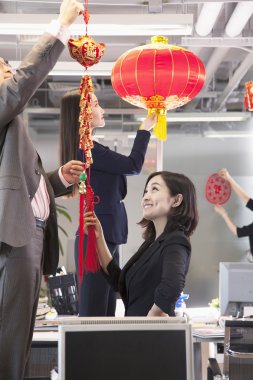 Coworkers hanging decorations for Chinese new year clipart