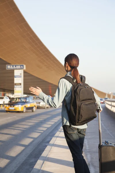 Traveler hailing a taxi at airport — Stock Photo, Image