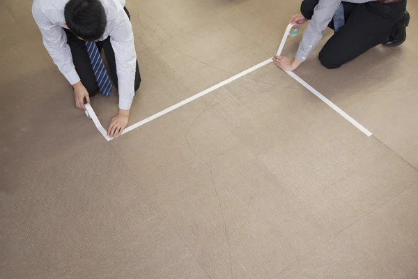 Businessmen taping up the floor in the office — Stock Photo, Image