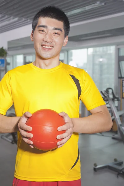 Homme tenant le ballon dans ses mains dans la salle de gym — Photo