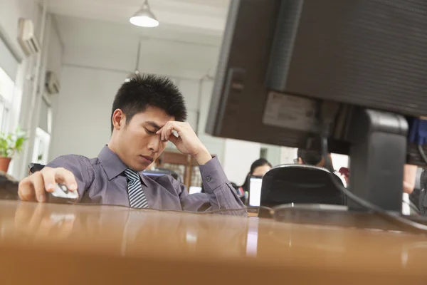 Exhausted businessman sitting in front of computer — Stock Photo, Image