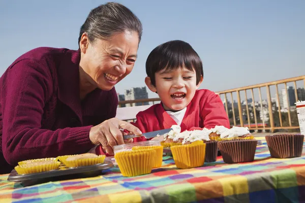 Oma en kleinzoon versieren cupcakes — Stockfoto