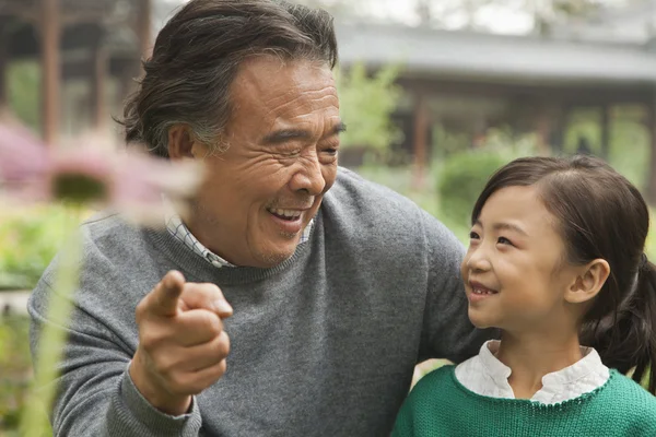 Grand-père et petite-fille regardant la fleur dans le jardin — Photo