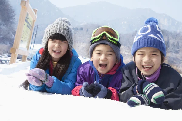 Niños acostados en la nieve — Foto de Stock