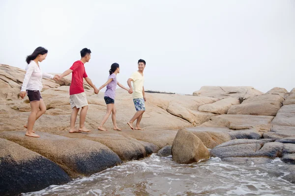 Amigos caminhando sobre rochas junto ao mar — Fotografia de Stock