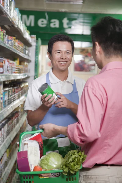 Verkäuferin hilft Mann im Supermarkt — Stockfoto