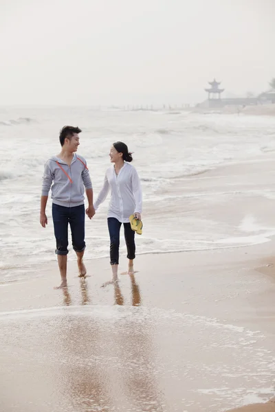 夫妻在沙滩上散步的水域的边缘 — 图库照片