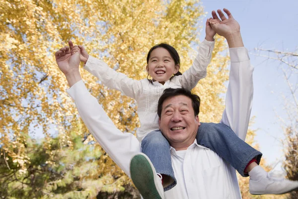 Abuelo llevando a su nieta en los hombros — Foto de Stock