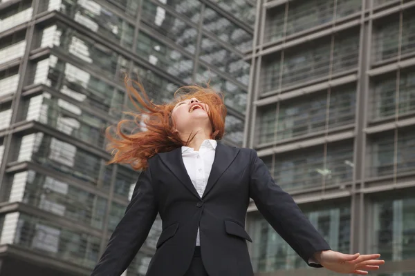 Mujer de negocios mirando hacia arriba con viento soplando en su cabello — Foto de Stock