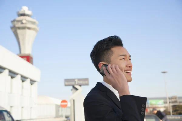 Reiziger praten over cellphone buiten op de luchthaven — Stockfoto